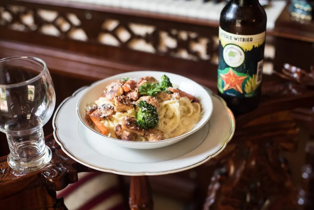 Fresh pasta in a white bowl beside a Maritime craft beer